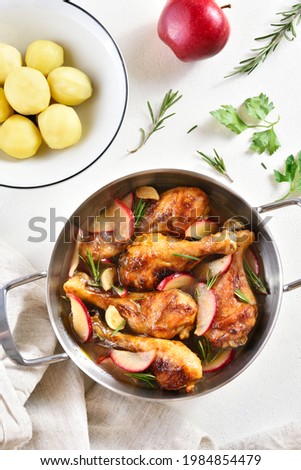 Chicken drumsticks baked with apples and herbs. White background, top view, flat lay