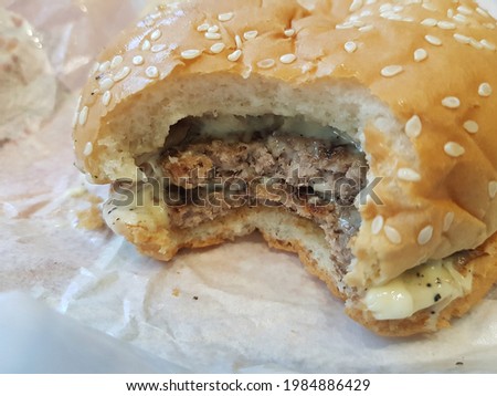 A hamburger was bitten deeply in the middle.