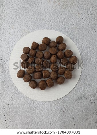 5mm fish feed pellet on round white filter whatman paper. Suitable for fish broodstock. Floating pellet for freshwater fish. Grey marble background. Almost round shape.