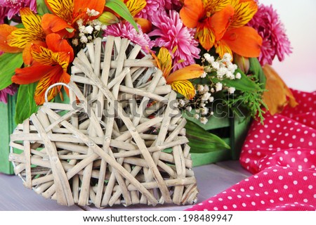 Flowers composition in crate with decorative heart on table close up