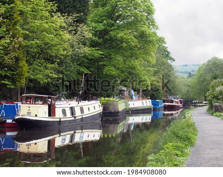 canal boats moored opposite the path on the rochdale canal near hebden bridge surrounded by trees in summer Royalty-Free Stock Photo #1984908080