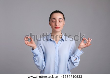 Young woman meditating on light grey background. Personality concept