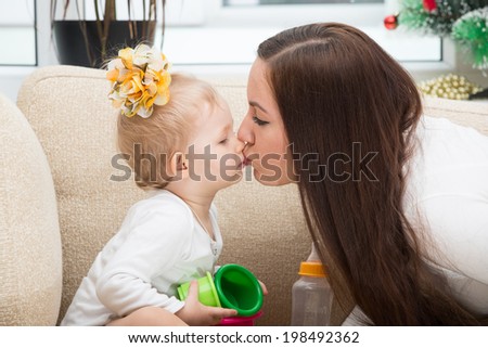 Happy mom and child girl hugging and kissing at home. The concept of cheerful childhood and family. Beautiful Mother and her baby