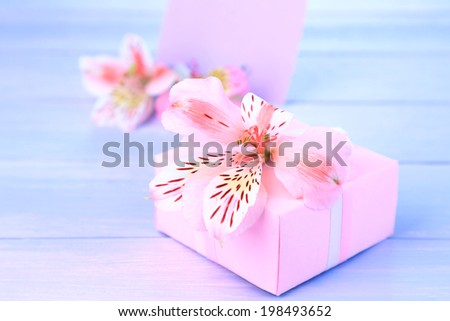 Pink gift with bow and flower on wooden table close-up