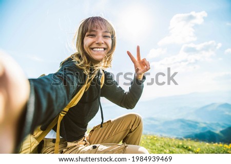 Young woman taking selfie portrait hiking mountains - Happy hiker on the top of the cliff smiling at camera - Travel and hobby concept Royalty-Free Stock Photo #1984939469