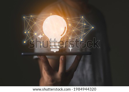 A business man holding the smart device and computer graphic such light idea icon and stroke line connection and orange light, success and business concept