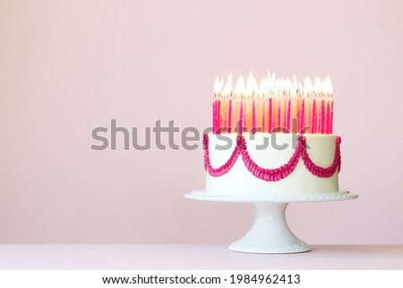 Birthday cake with lots of pink birthday candles on a pink background