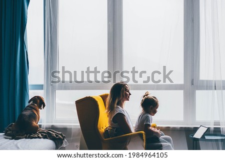 Mom with little daughter looking to the digital tablet. 