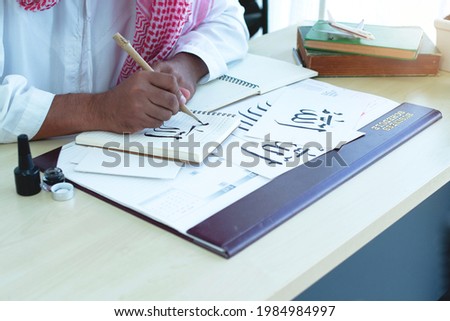 Arab men practicing writing Arabic  with bamboo pens and ink on paper, Arabic letters mean the name of Muslim god "Allah", handwriting Khat