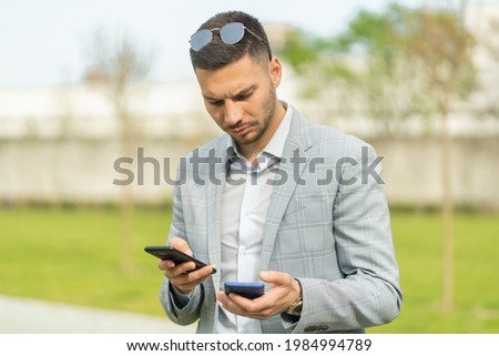 Handsome and attractive businessman is holding two phones