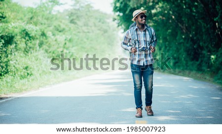 Traveling african male tourist backpacker walking on the highway road.Adventure travel concept
