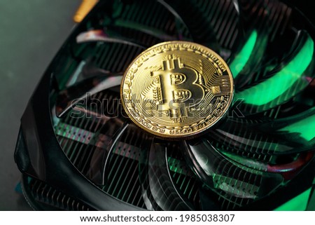 Gold bitcoin on the video card cooler with green neon lighting in the Cyberpunk style.