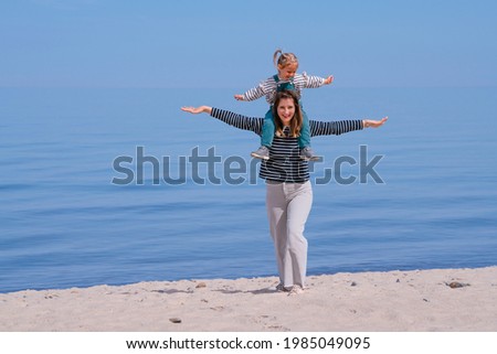 Happy mother and daughter standing and hugging on the beach 
