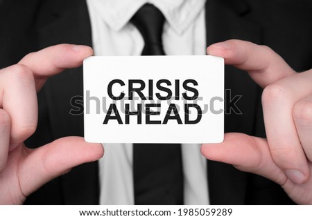 Businessman holding a card with text CRISIS AHEAD