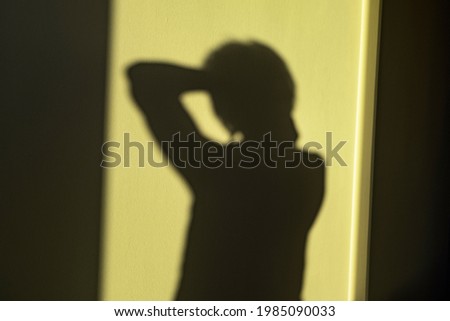 Woman shadow on yellow wall as mental health, lonely person concept, no focus, smooth shut Royalty-Free Stock Photo #1985090033