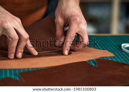 Tailor's hands a purchase plan, a partner tries on a detail of a leather product, a leather steam room collects a leather bag from parts, a tailor business