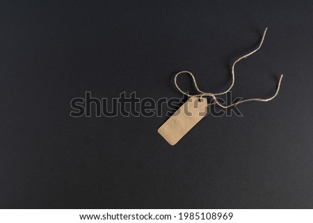 On a dark background, an empty shopping label, a price tag made of craft paper with a rope. Mockup, advertising flyer. Place for your text. Horizontal photo. 