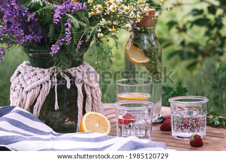 breakfast in the garden. on the table is a vase of flowers and glasses of lemonade
