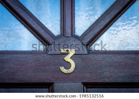 House door number 3 on a  dark wooden front door with glass