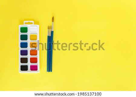 Paints and brushes on a yellow background.Back to school. The concept of education. Everything for school and office. School supplies. The child will draw Flatly. From above. Copy space