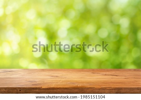 Old wooden table top with defocused sunny green background