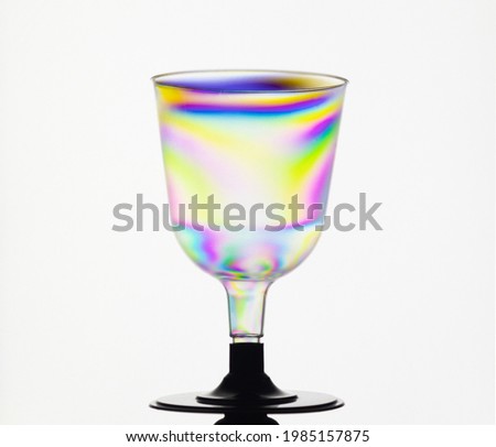 Transparent plastic cup, rainbow colored by photo elasticity isolated on white background. Synthwave  polarized modern futuristic look.