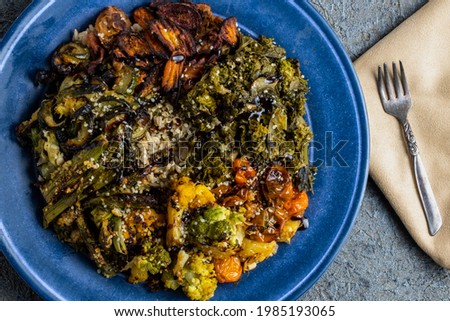 Brown Rice Plate with Roasted Veggies Including Rainbow Tomatoes, Orange Cauliflower, Romanesco Broccoli, Kale, and Asparagus on a Blue Plate