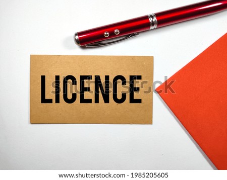 Business concept. Brown card with text LICENCE with pen on red and white background