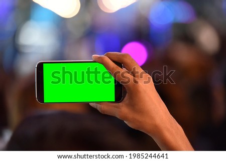 Hand holding mobile phone with chroma key screen
