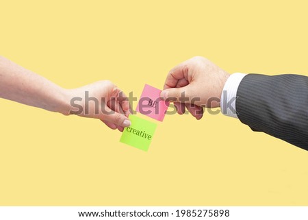 Two hands hold two sticky notes with the words Be and Creative. Conceptual image of basic concepts for creativity.
