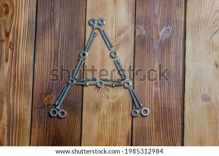 letters A of english alfabet made from bolts, screws and nuts on the wooden background