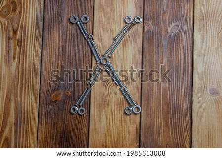 letters X of english alfabet made from bolts, screws and nuts on the wooden background