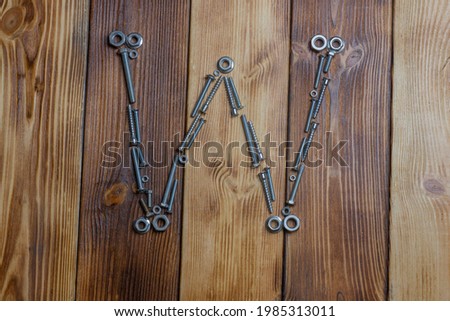 letters W of english alfabet made from bolts, screws and nuts on the wooden background