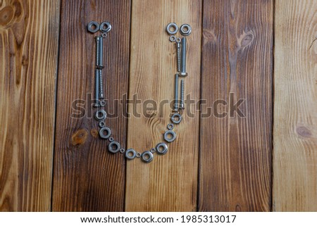 letters of english alfabet made from bolts, screws and nuts on the wooden background