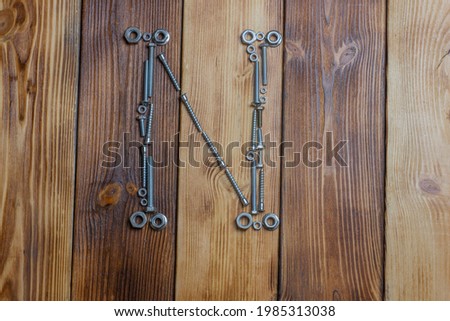 letters N of english alfabet made from bolts, screws and nuts on the wooden background