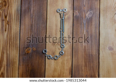 letters J of english alfabet made from bolts, screws and nuts on the wooden background