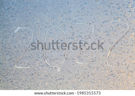 the inscription about the new year 2022 on the frozen window glass in winter