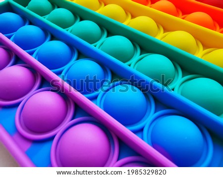 Anti-stress toy poppit. Push bubble toy. Rainbow colors. Close-up. Colored abstract background. Royalty-Free Stock Photo #1985329820
