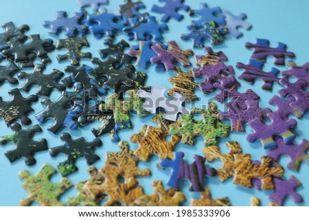 White jigsaw puzzle on colorful pieces of incomplete jigsaw puzzles on blue background, selective focus. Team business solutions, success and strategy concept.