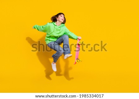 Full length body size view of pretty cheery girl jumping riding skate having fun spare time isolated over bright yellow color background