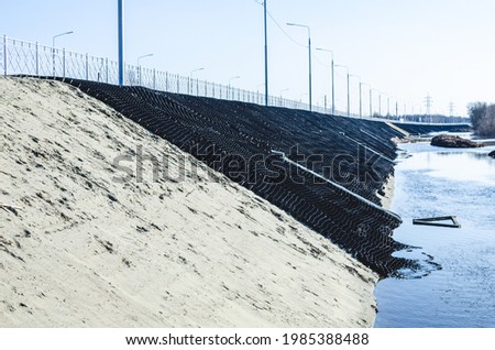 Industrial geocells in operation. Black geogrid filled with soil for stability of steep hill Royalty-Free Stock Photo #1985388488