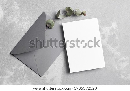 Greeting or wedding invitation card mockup with envelope and dry eucalyptus twig, top view, copy space