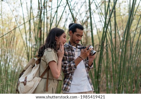 Male and female tourists are touring nature and taking pictures of the scenery. Couples go wild together on weekends. Nature tourism concept.