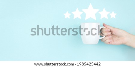 Customer Experience Concept. Girl hand hold morning coffee cup with Five stars 5 rating sign Icon on blue background. Increase rating evaluation and classification concept.