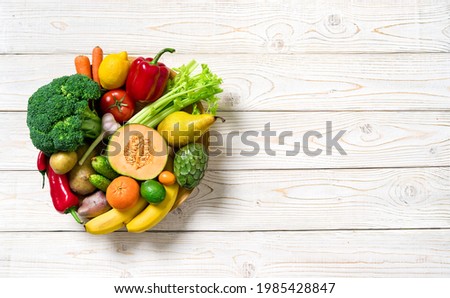 Plate with vegetables and fruits on wooden table. Healthy food, top view. Royalty-Free Stock Photo #1985428847