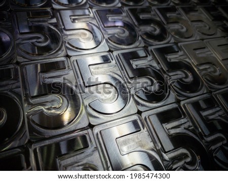 shiny metal machined digit 5 plates tiled tightly - full frame background Royalty-Free Stock Photo #1985474300