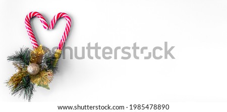 Spruce branch with Christmas decorations and caramel staffs on a white background. Banner. Postcard. The concept of New Year holidays. Copy space.