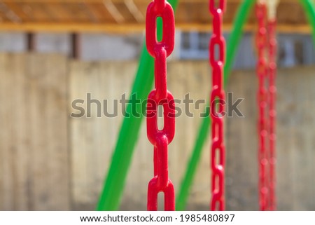 Chains covered with red rubber coating for safety on swings in the playground.