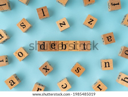 Debit word on wooden block. Flat lay view on blue background.