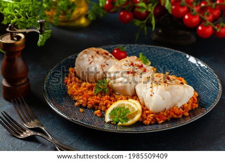 Fried pieces of cod loin, served on dark chickpeas. Dark painted background.